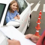 Mladá řidička s mírně tázavým výrazem za volantem, zkoumající zrcátka před parkováním, což ilustruje nejčastější chyby začínajících řidičů.