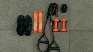 Šťastný pár drží různé sportovní vybavení, které představuje, jak vybrat správné sportovní vybavení pro začátečníky. Žena ukazuje na boty, muž drží raketu.