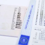 Pila de documentos esenciales para tu vehículo, como la licencia de conducir, tarjeta de registro y seguro, cuidadosamente apilados en una mesa.