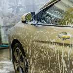 Automaattipesusta ja käsinpesusta yhdistetty kuva, jossa näkyy auton puhdistus molemmilla tavoilla. Havainnollistaa autopesu-vaihtoehtoja selkeästi.