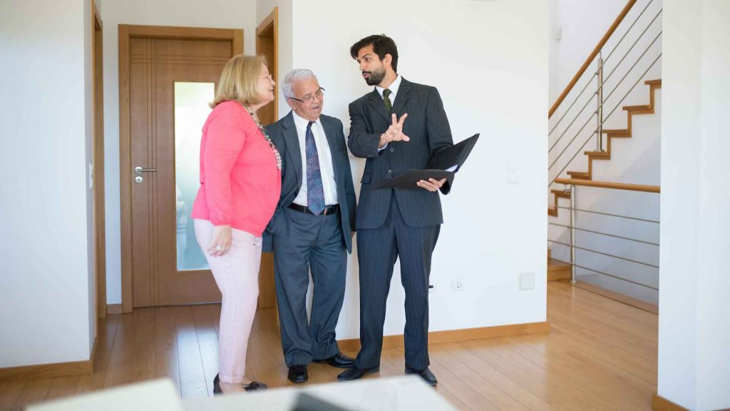 Couple de personnes âgées discutant avec un agent immobilier.
