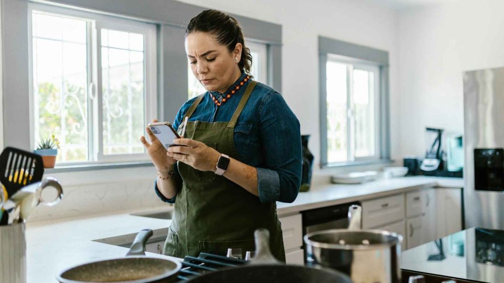 Une femme utilise un téléphone portable pour trouver une recette adaptée.