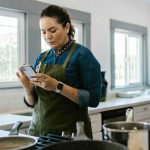 Une femme utilise un téléphone portable pour trouver une recette adaptée.