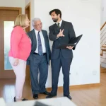 Συζήτηση σε γραφείο με έναν μεσίτη ακινήτων που εξηγεί τη διαδικασία επιλογής μεσίτη και τα σημαντικά κριτήρια που καθορίζουν τον ρόλο του.