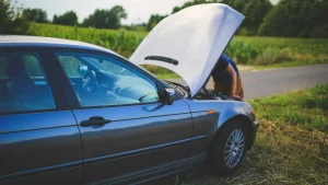 Automobilista con giubbotto catarifrangente segnala un guasto auto su strada usando il triangolo di emergenza. Il veicolo è fermo sul ciglio della carreggiata.