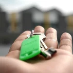 Persoană consultă un ghid închiriere locuințe pe tabletă. Chei și contract pe masă. Pregătiri pentru mutare.