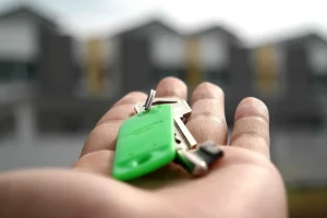 Persoană consultă un ghid închiriere locuințe pe tabletă. Chei și contract pe masă. Pregătiri pentru mutare.