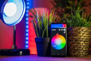 Diverse dispozitive smart home: termostat, boxă vocală și priză inteligentă, aranjate clar pe o masă.