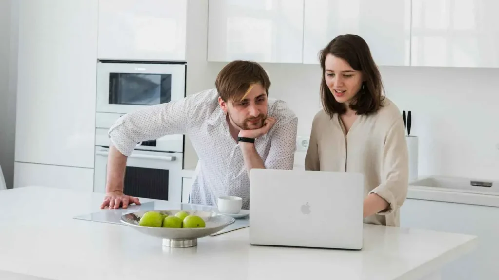 En person sitter vid ett bord med en laptop och papper, symboliserande processen för bostadssökning och granskning av hyresavtal.