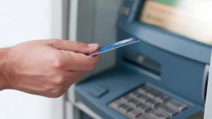 Osoba wkładająca kartę płatniczą do bankomatu.
