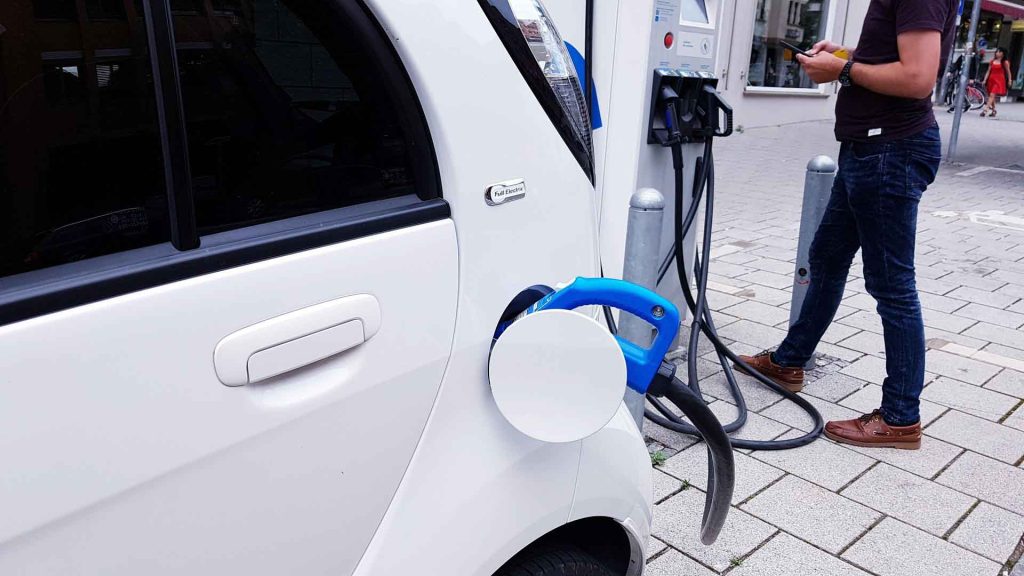Osoba ładująca samochód elektryczny.
