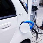Osoba ładująca samochód elektryczny.
