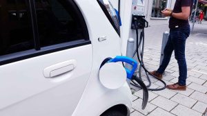 Osoba ładująca samochód elektryczny.